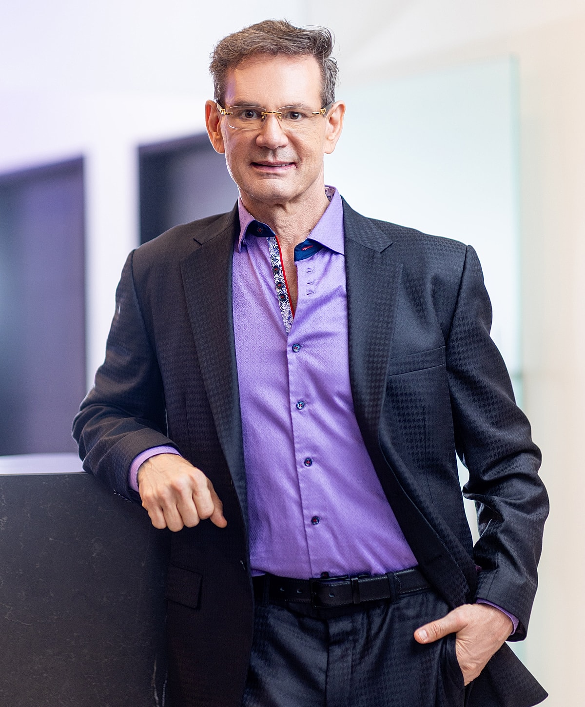 Man in a suit posing confidently indoors.