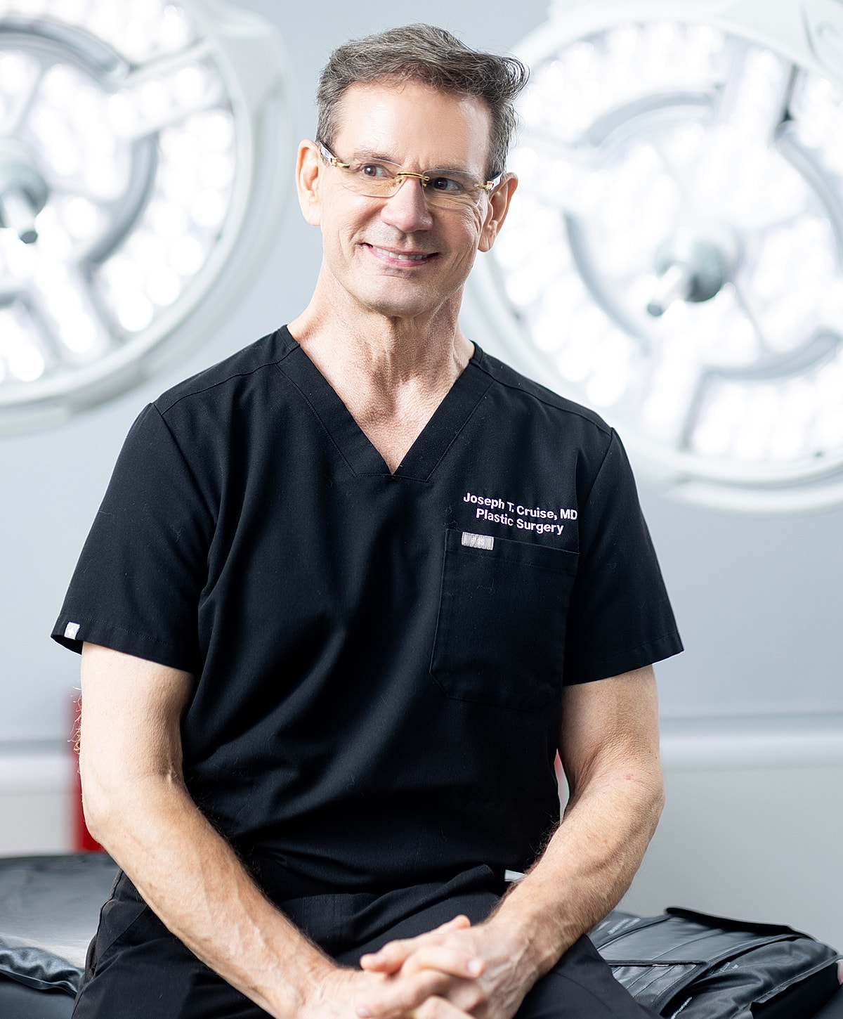 Doctor in scrubs smiling in surgical setting.