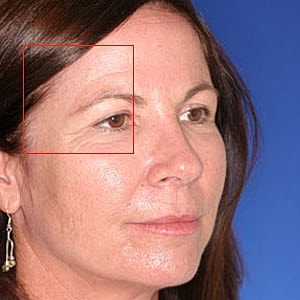 Close-up of woman’s face against blue background.