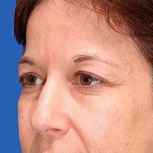 Close-up of a woman's face against blue backdrop.