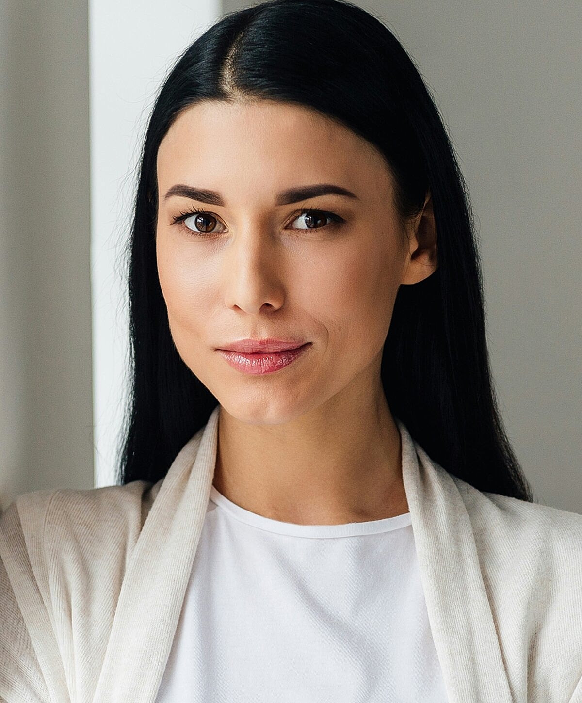 Woman with long hair, wearing a light cardigan.