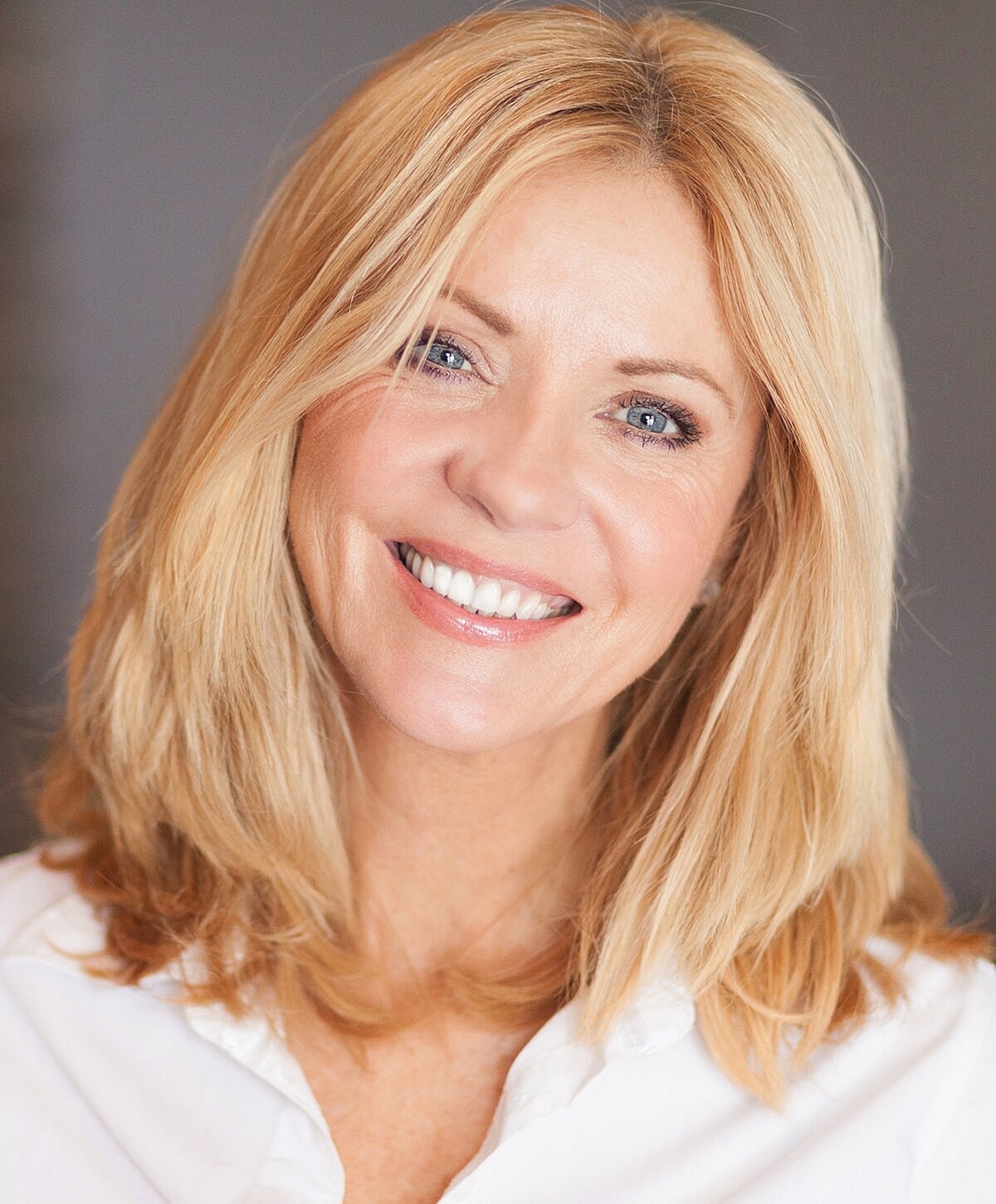 Smiling woman with blonde hair and white shirt.