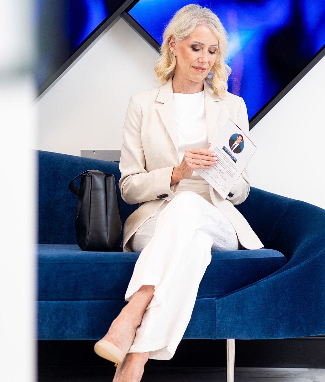 Woman reading document on a blue couch.
