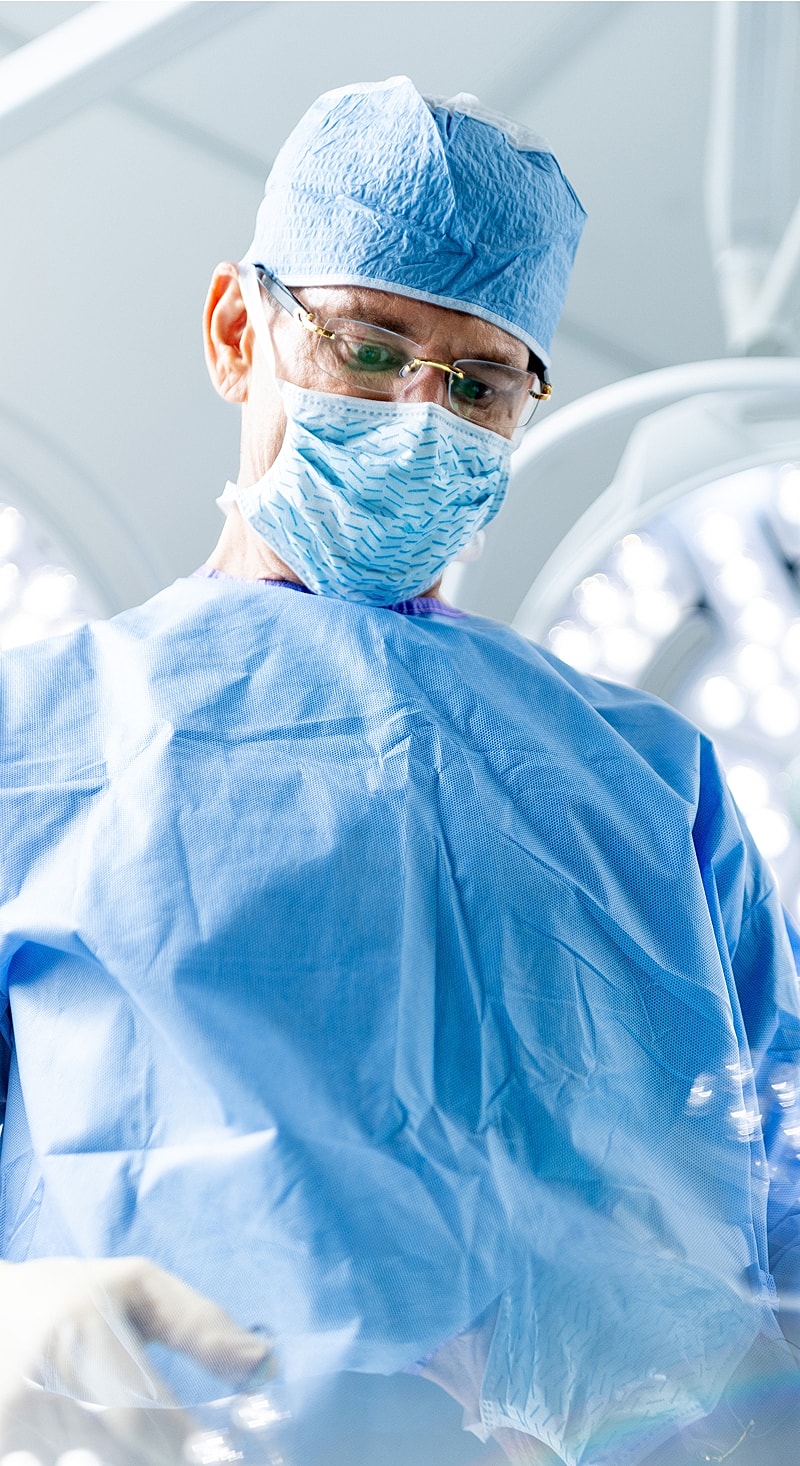 Surgeon in scrubs performing a medical procedure.