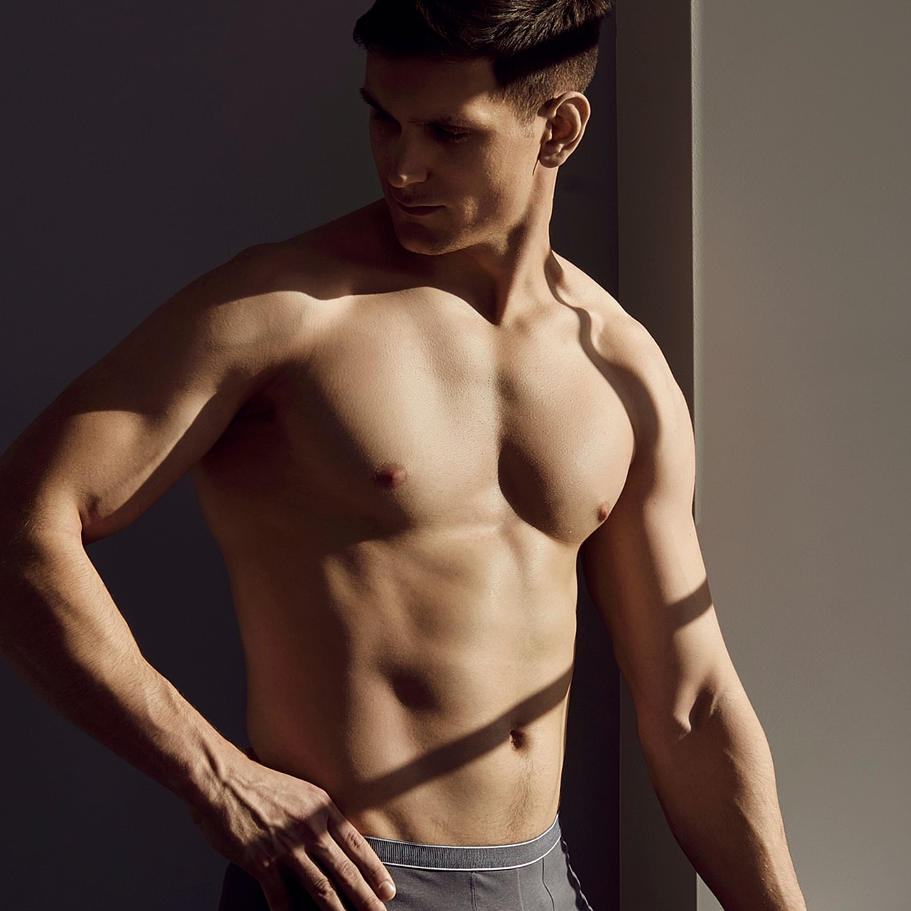 Man posed against light and shadow background.