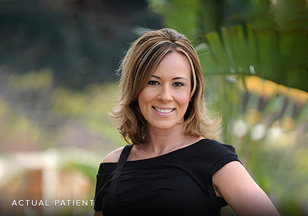 Smiling woman outdoors with green background.
