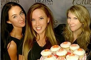 Friends posing with cupcakes at an event.