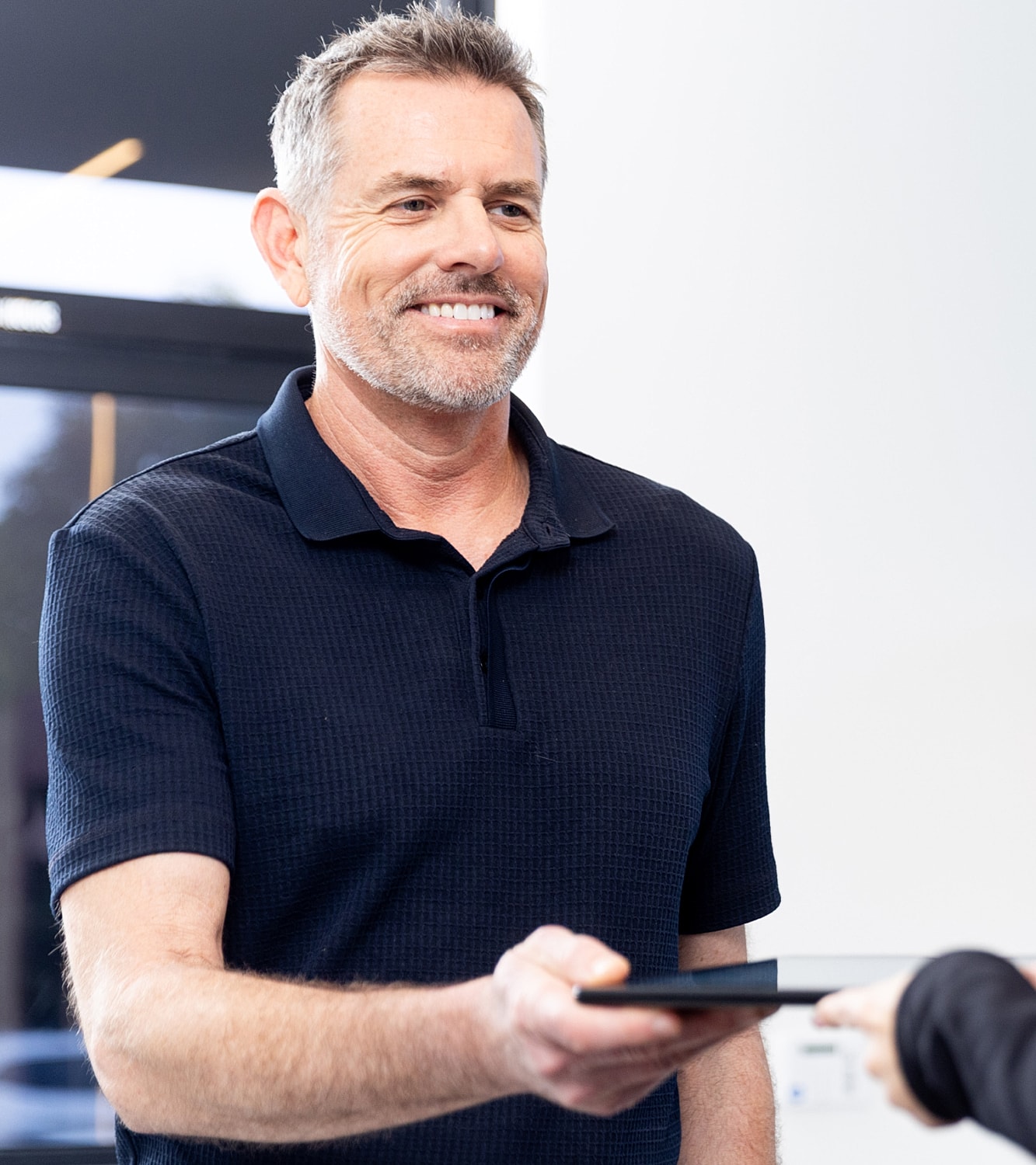Man smiling while receiving a tablet device.