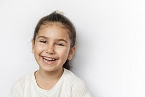 Smiling girl with brown hair and white background.
