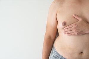 Bare torso with hand on chest.