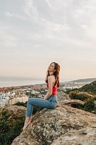 Woman sitting on rock overlooking a city.