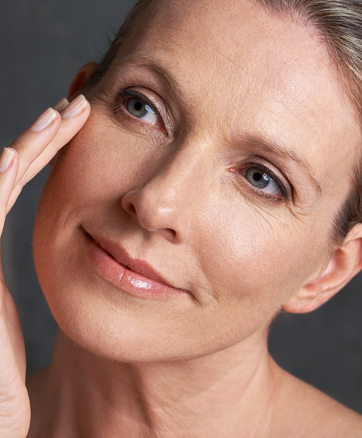 Woman touching her face, smiling gently.