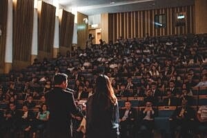 Audience watches speakers in a conference setting.