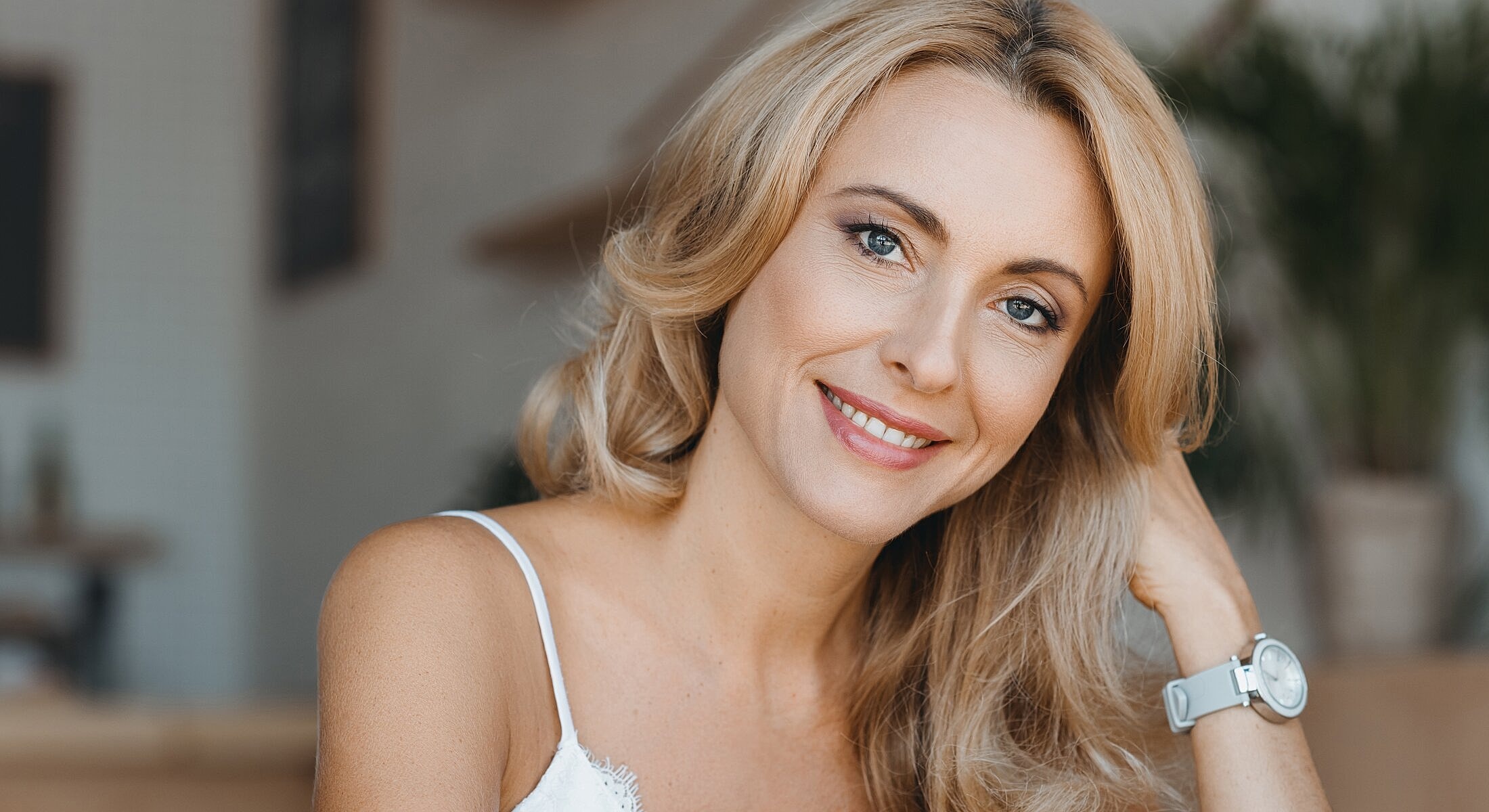 Smiling woman with long blonde hair indoors.