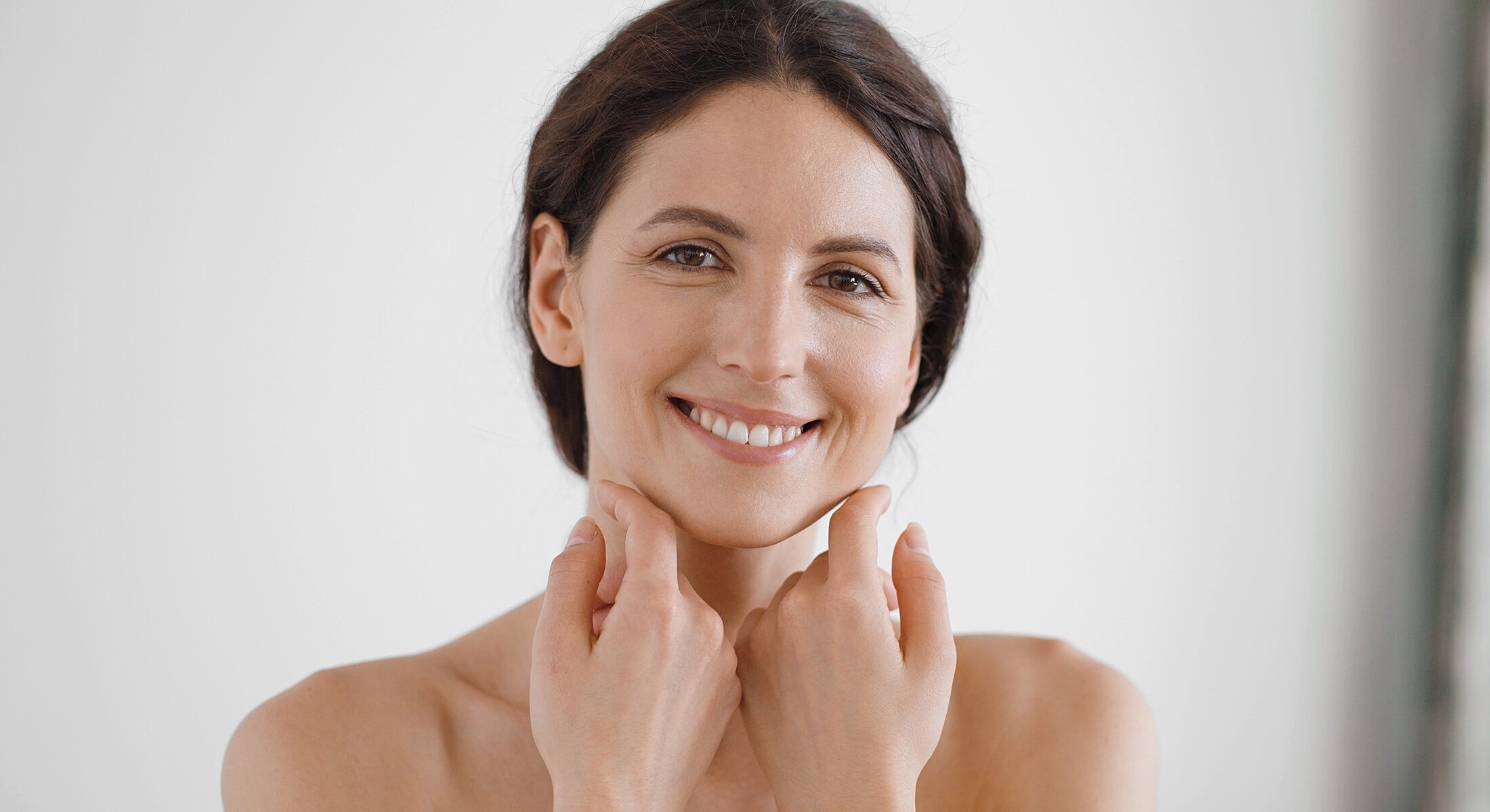 Newport Beach buccal fat removal model touching her face gently