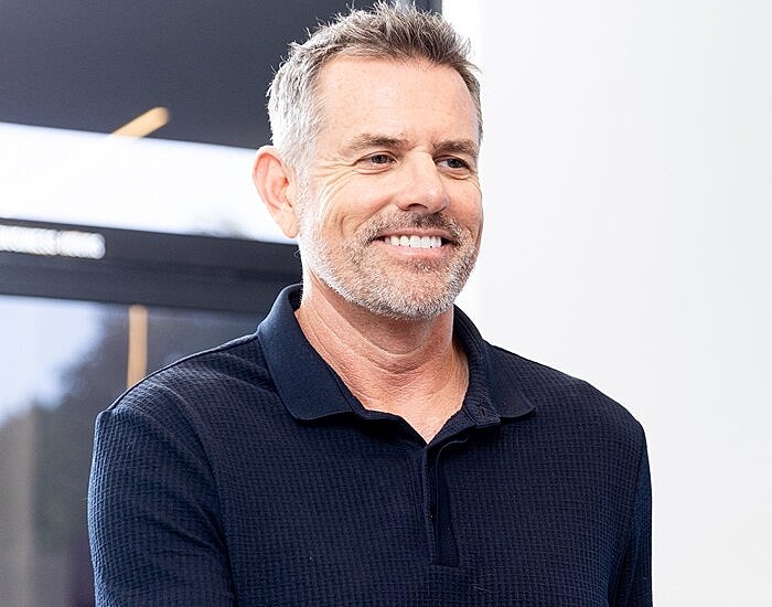 Smiling man in a dark polo shirt.