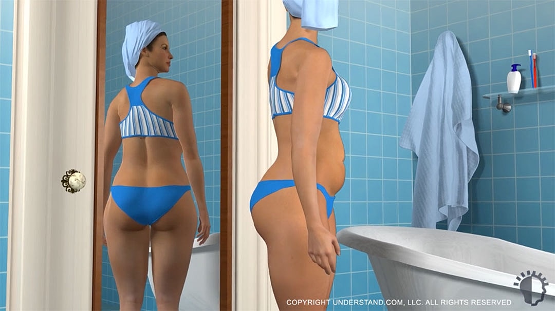 Woman in bathroom wearing blue swimsuit, towel.