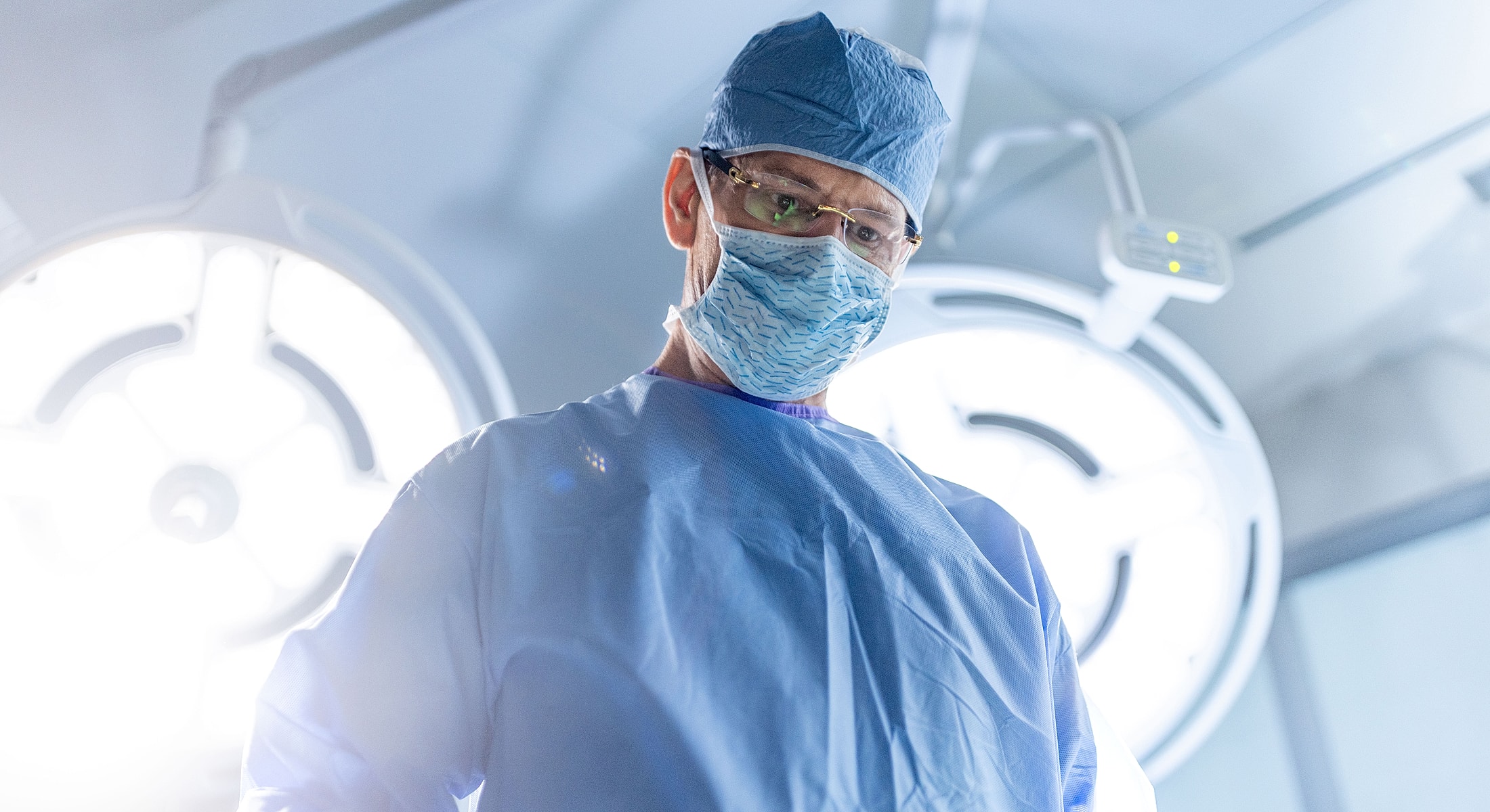 Surgeon in operating room wearing protective gear.